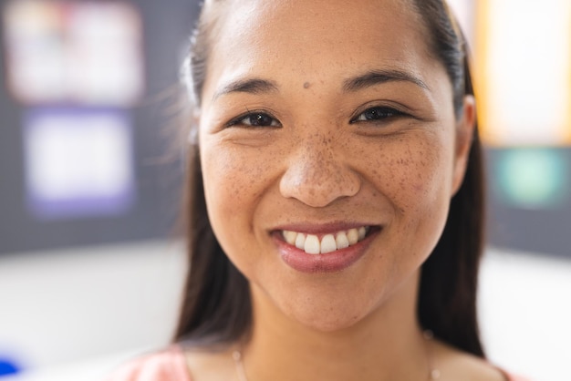 A young biracial female teacher with freckles is smiling in a classroom