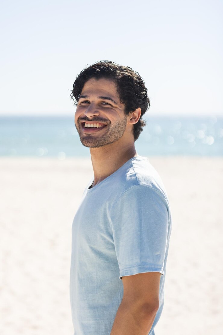 Photo a young biracial man smiles brightly at the beach