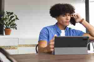 Photo young biracial man talking on phone looking at tablet