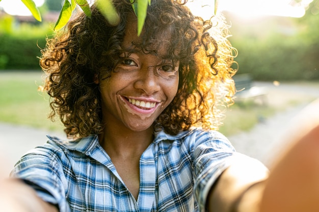 Young biracial woman taking selfie on sunset outside female person with genetic vitiligo smiling at the camera happy people and body positive concepts