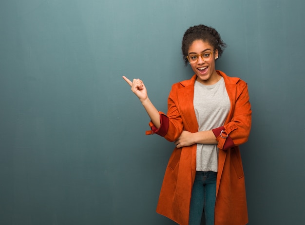 Young black african american girl with blue eyes pointing to the side with finger