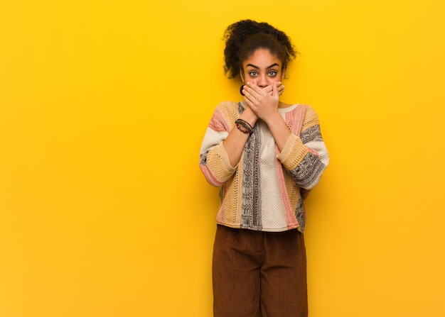 Young black african american girl with blue eyes surprised and shocked