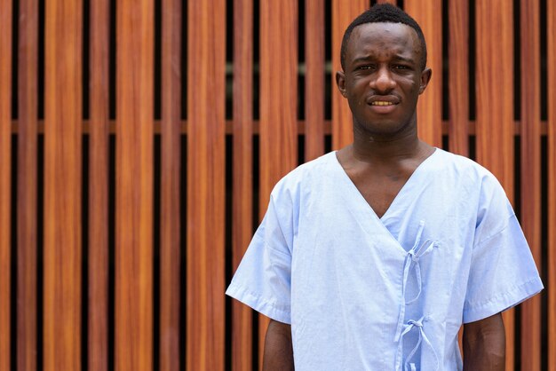 young black African man patient against wooden wall