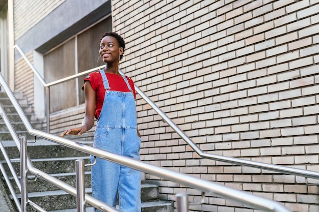 Young black African model woman smiling and walking down the stairs of her house door