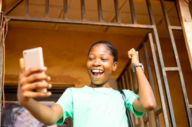 Young black african woman checking content on social media chatting with friend online using cellphone