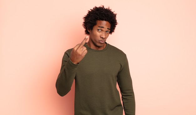 Photo young black afro man feeling angry, annoyed, rebellious and aggressive, flipping the middle finger, fighting back