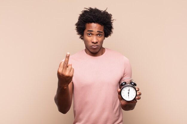 Young black afro man feeling angry, annoyed, rebellious and aggressive, flipping the middle finger, fighting back