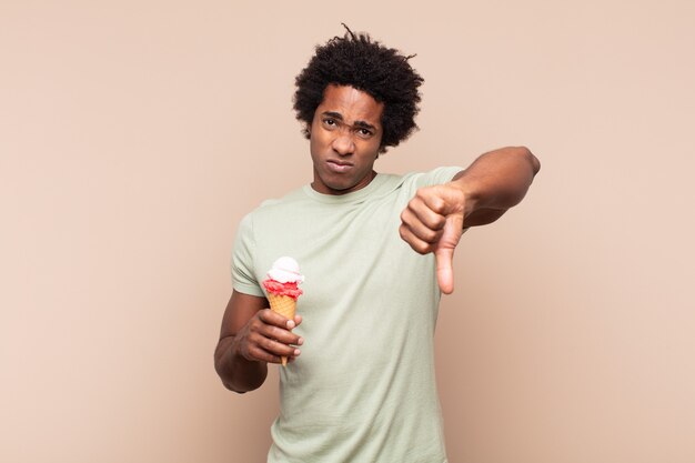 Young black afro man feeling cross, angry, annoyed, disappointed or displeased, showing thumbs down with a serious look