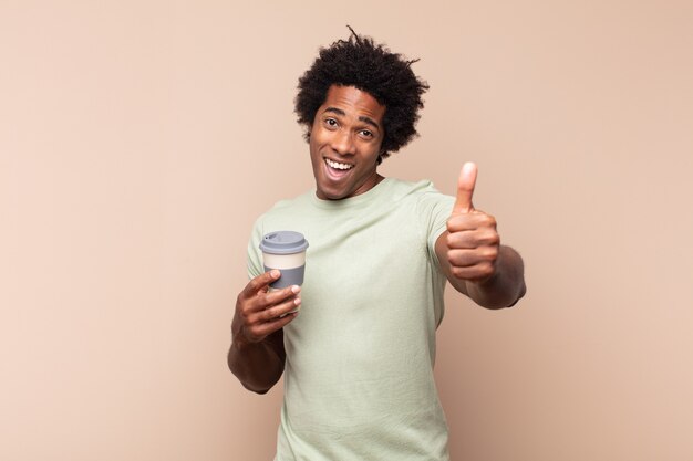 Young black afro man feeling proud, carefree, confident and happy, smiling positively with thumbs up