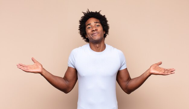 Young black afro man laughing out loud at some hilarious joke, feeling happy and cheerful, having fun