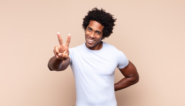 Young black afro man looking sad, disappointed or angry, showing thumbs down in disagreement, feeling frustrated