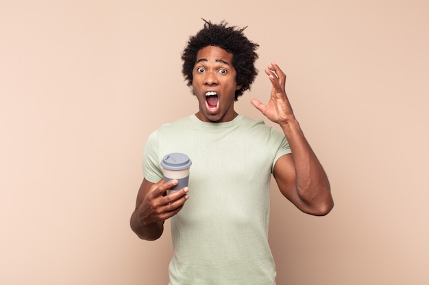 young black afro man screaming with hands up in the air, feeling furious, frustrated, stressed and upset