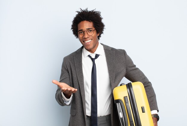 Young black afro man smiling happily with friendly, confident, positive look, offering and showing an object