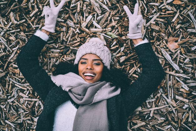 Young black beautiful woman lying on peaces of wood near the royal palace in Madrid during winter