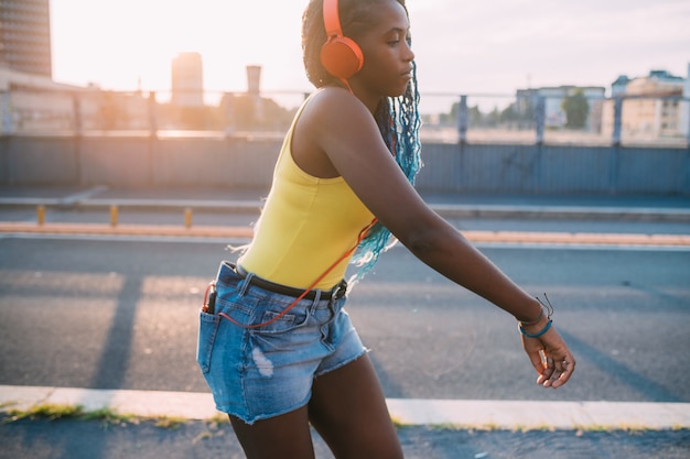 Young black beautiful woman outdoor listening music dancing