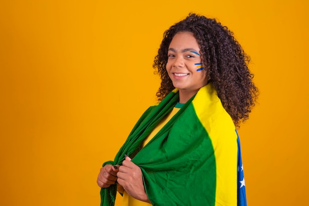 Young black brazilian cheerleader with the flag of Brazil happy