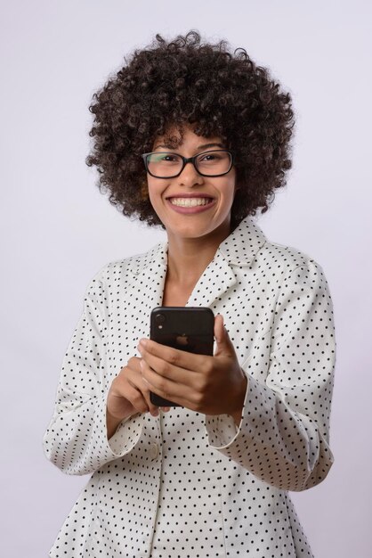 사진 젊은 흑인 브라질 여성이  셔츠를 입고 웃는 휴대전화를 들고 있다.