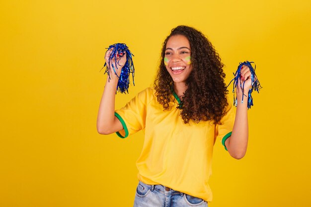 Young black brazilian woman soccer fan holding cheerleader pom poms