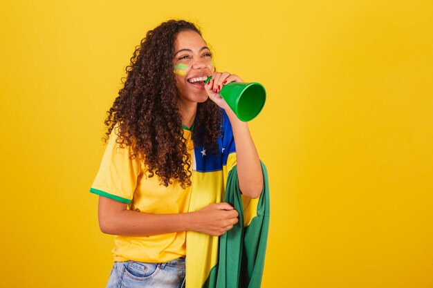 Foto giovane tifoso di calcio brasiliano nero che urla attraverso la foto pubblicitaria dell'altoparlante