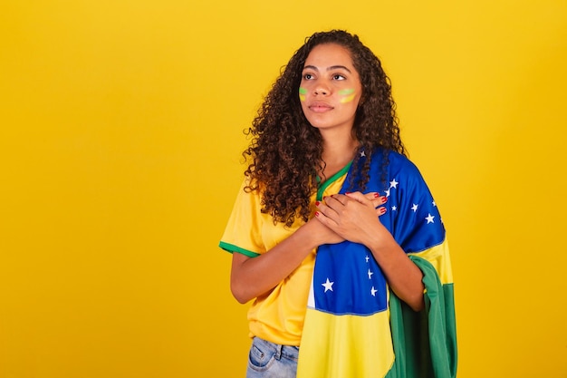 Young black Brazilian woman soccer fan with brazil flag singing the National Anthem