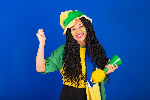 Young black Brazilian woman soccer fan with flag and accessories cheering