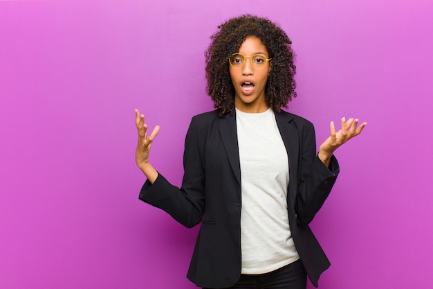 Young black business woman feeling extremely shocked and surprised, anxious and panicking, with a stressed and horrified look