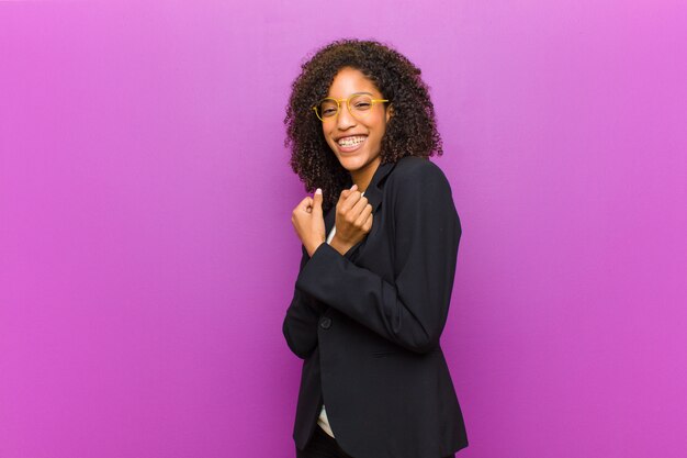 Photo young black business woman smiling cheerfully and celebrating, with fists clenched and arms crossed, feeling happy and positive