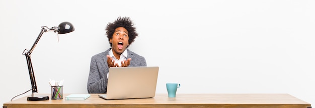 Young black businessman looking desperate and frustrated stressed unhappy and annoyed shouting and screaming