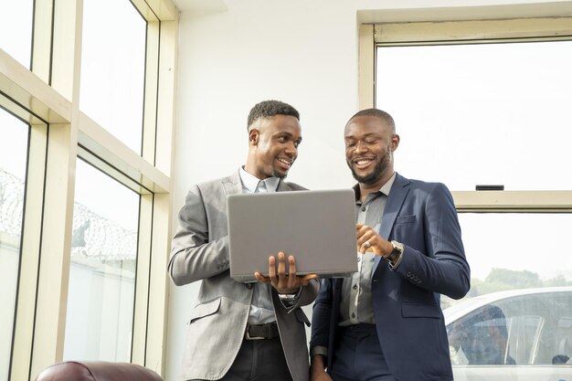 Young black businessmen standing together holding a laptop discussing business