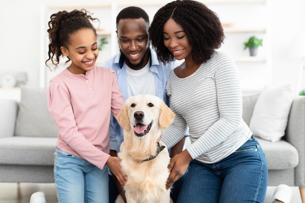 家でポーズをとって犬と抱き締める若い黒人家族