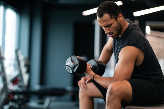 Young Black Male Athlete Training With Dumbbell Making Seated Biceps Curl