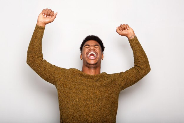 young black man cheering with arms raised against gray background