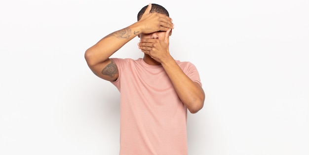 Young black man covering face with both hands saying no