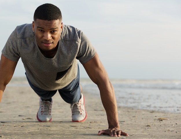 Young black man doing push ups at the beach