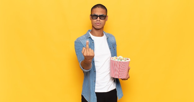 Young black man feeling angry, annoyed, rebellious and aggressive, flipping the middle finger, fighting back