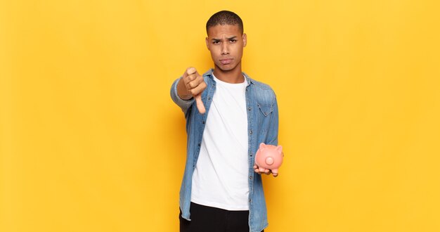 Young black man feeling cross, angry, annoyed, disappointed or displeased, showing thumbs down with a serious look