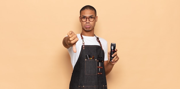 Young black man feeling cross, angry, annoyed, disappointed or displeased, showing thumbs down with a serious look