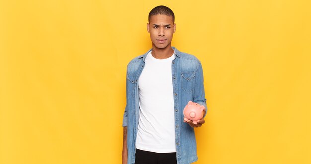 Young black man feeling sad, upset or angry and looking to the side with a negative attitude, frowning in disagreement