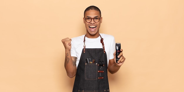 Young black man feeling shocked, excited and happy, laughing and celebrating success, saying wow!