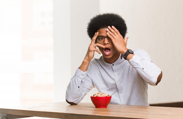 Young black man having a breakfast feels worried and scared