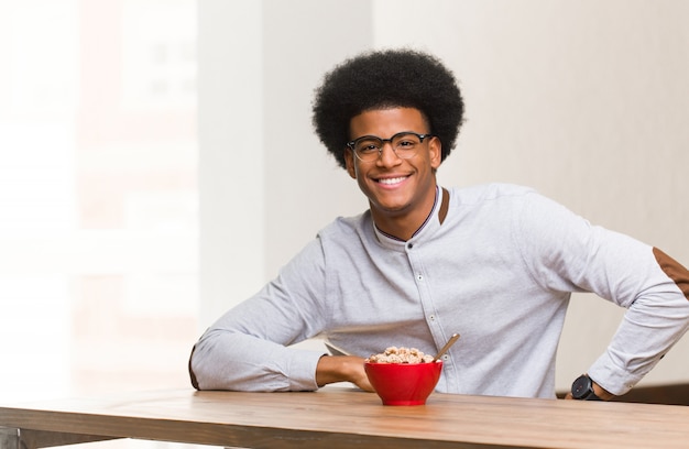 Young black man having a breakfast with hands on hips