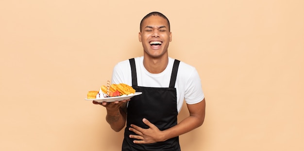 Young black man laughing out loud at some hilarious joke, feeling happy and cheerful, having fun