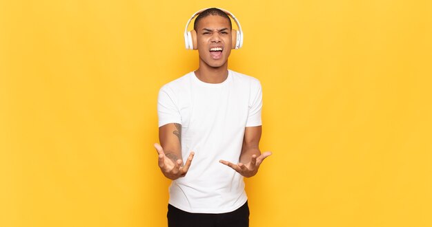 Young black man looking angry, annoyed and frustrated screaming wtf