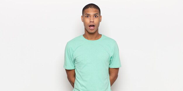 Young black man looking very shocked or surprised, staring with open mouth saying wow