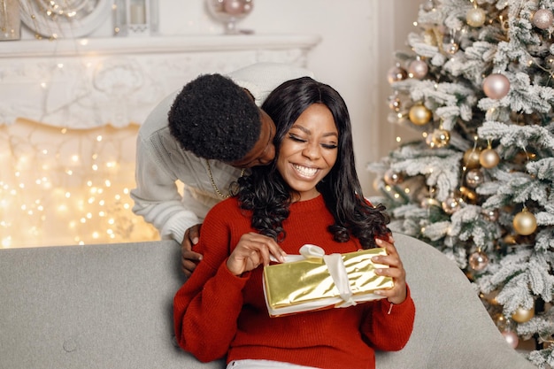 Молодой темнокожий мужчина делает сюрприз своей девушке в канун Рождества