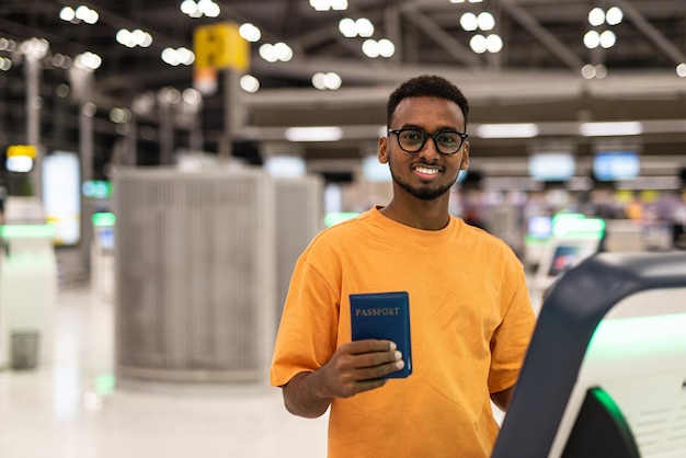 フライトを待っている空港ターミナルで旅行する準備ができている若い黒人男性