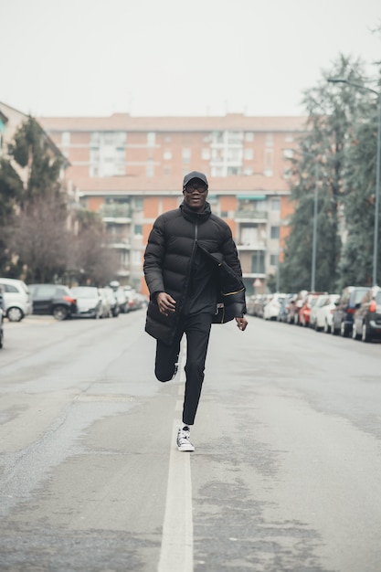 Giovane uomo di colore che corre in strada e guardando oltre