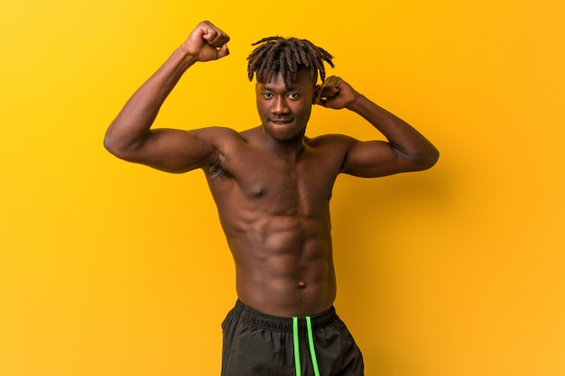 Young black man shirtless wearing swimsuit celebrating a special day, jumps and raising arms with energy.