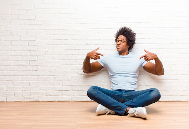 Young black man sitting on the floor with a copy space