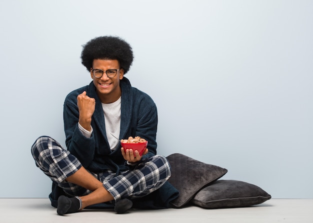 Young black man sitting and having a breakfast surprised and shocked